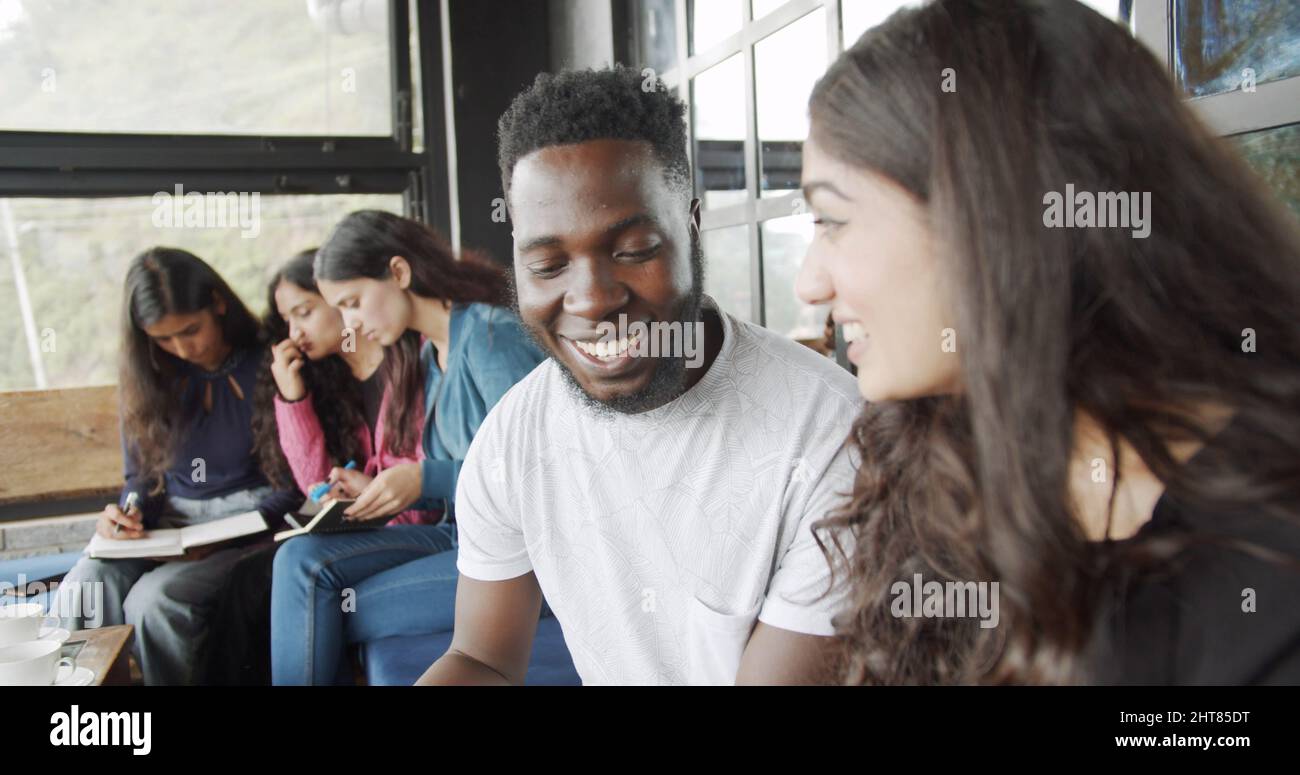 Smiling beautiful Indian woman talking to her male friend at a cafe Stock Photo