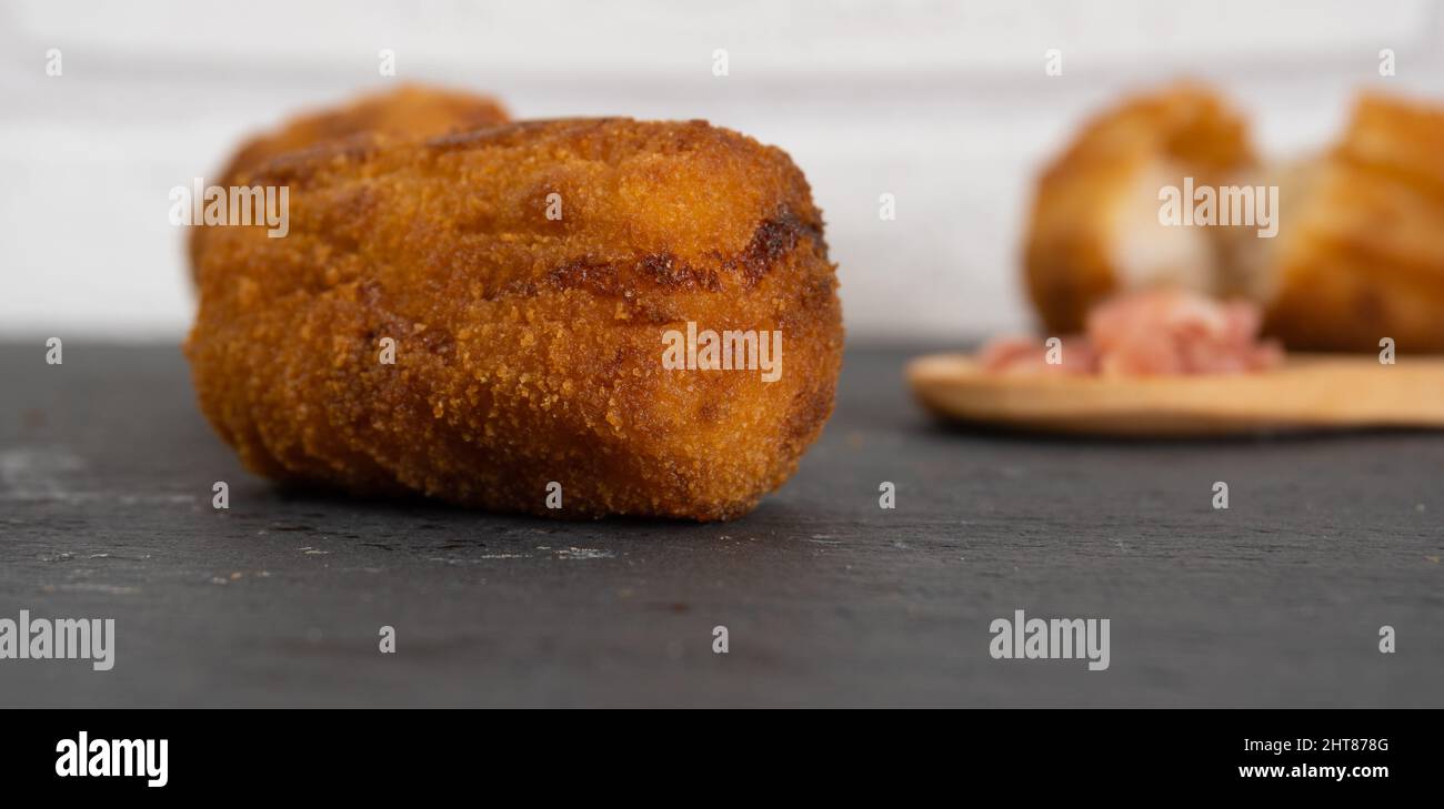 Closeup shot of a fried chicken nugget with ham croquettes in a wooden