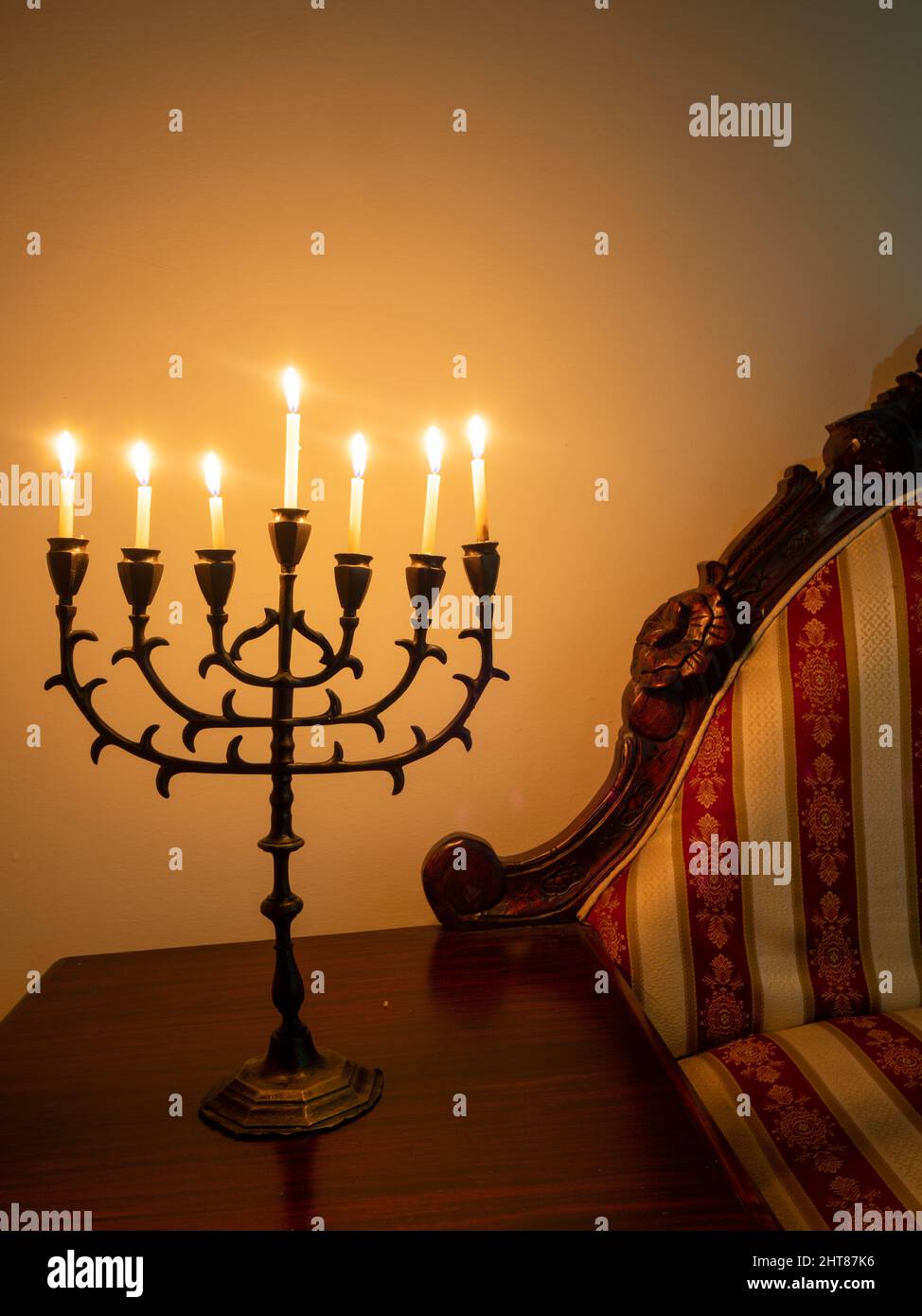 Closeup shot of a seven-branched candelabra with burning candles on the wooden table for Hanukkah Stock Photo