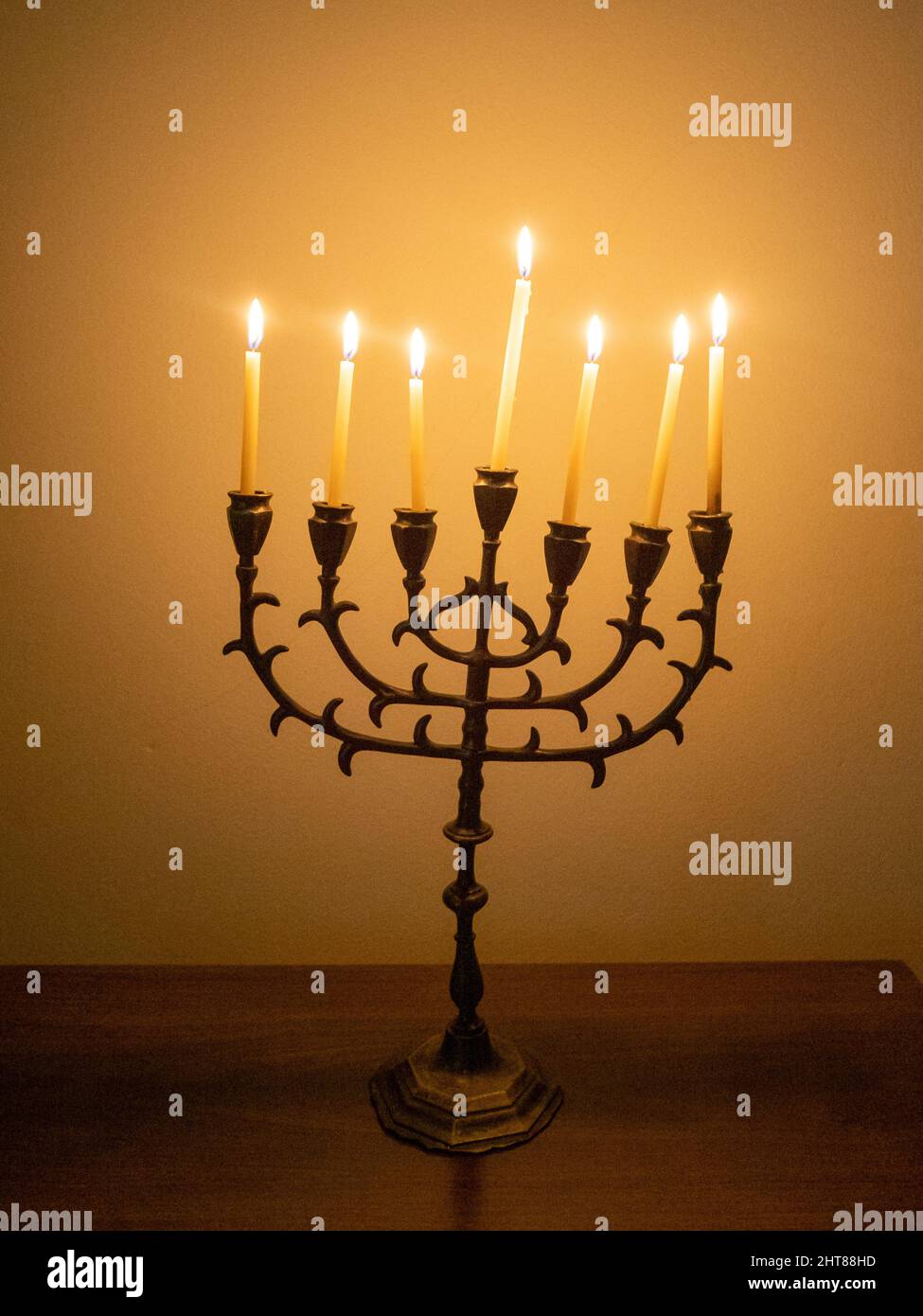 Closeup shot of a beautiful seven-branched candelabra with burning candles on the wooden table Stock Photo