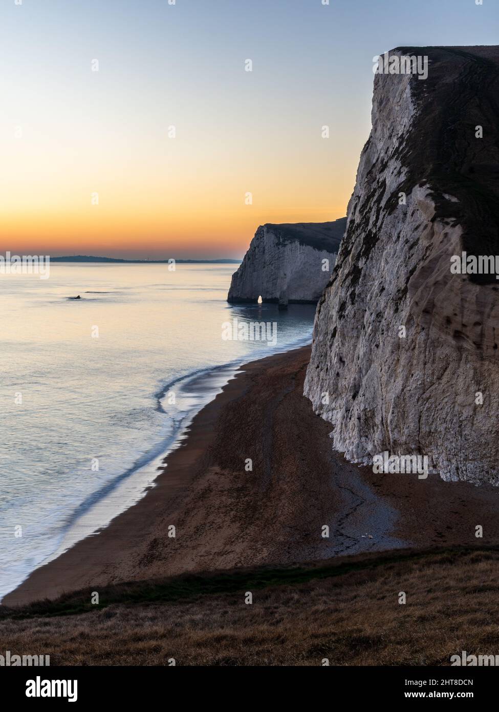 The sun sets over the chalk cliffs of Bat's Head near Lulworth on Dorset's Jurassic Coast. Stock Photo