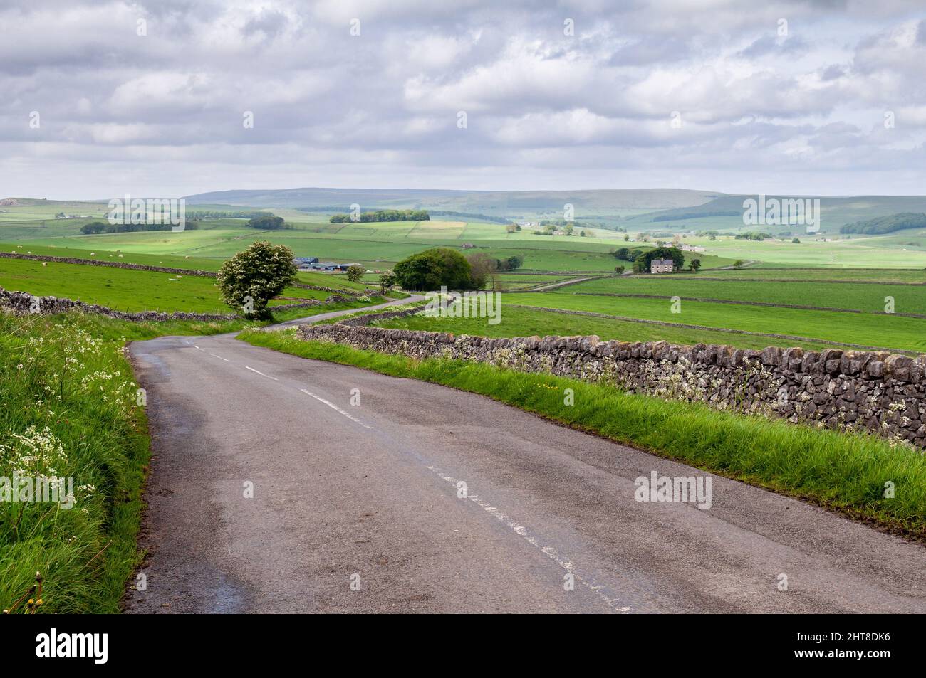 Farmland fields cover the rolling hills of England's Peak District, with the moors of Kinder Scout rising in the distance. Stock Photo