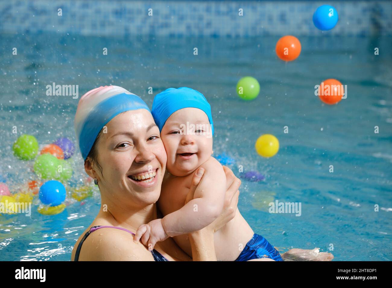 Early swimming coach training to swim baby boy in indoor pool. Playing