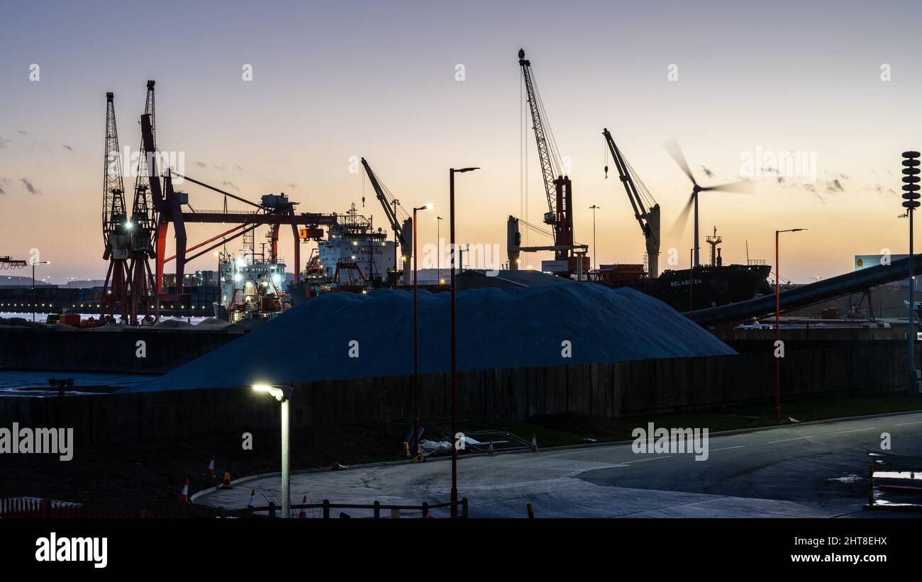 The sun sets over Avonmouth Docks while large bulk cargo ships are unloaded in Bristol. Stock Photo