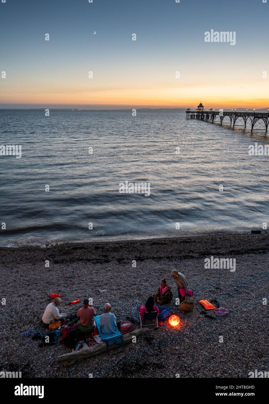 Swimmers gather at sunset on Clevedon Beach in Somerset, with Clevedon Pier and the Bristol Channel behind. Stock Photo