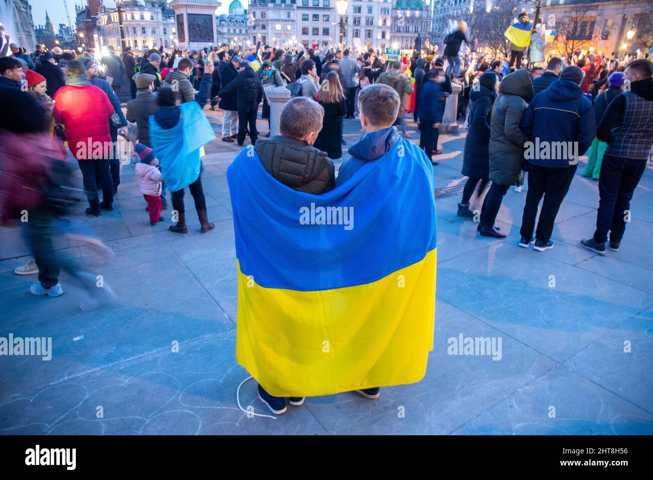 LONDON, FEBRUARY 27 2022 Two men draped in the ukrainian flag watch as Pro-Ukraine demonstrators hold protest against Russia's invasiom of the Ukraine on Trafalgar Square. Credit: Lucy North/Alamy Live News Stock Photo
