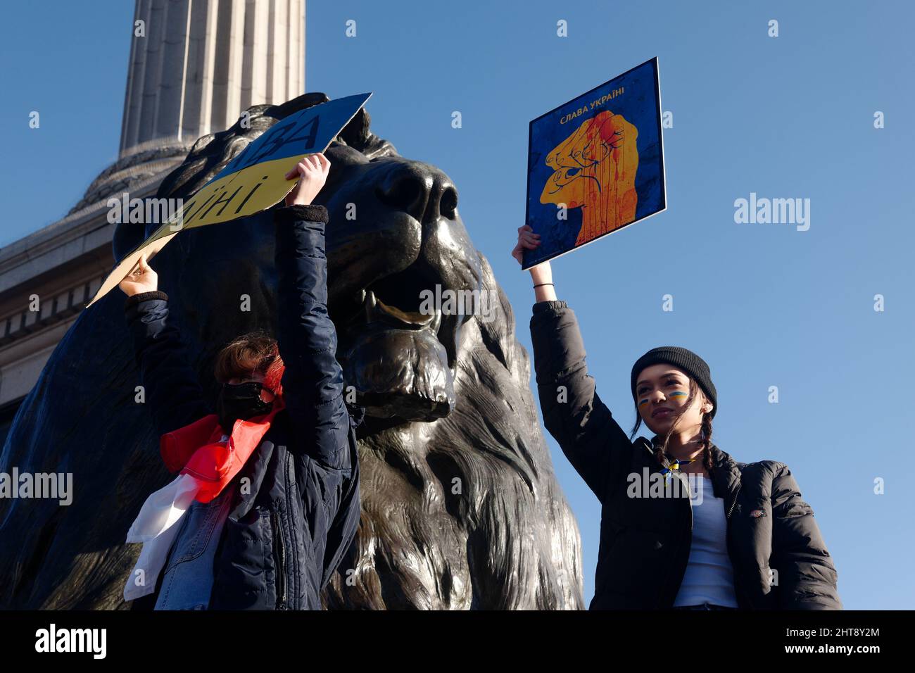 Two female protestors holding signs, protest against Russia's invasion of Ukraine, Trafalgar Square, Nelson's column, London, UK, 27 February 2022 Stock Photo