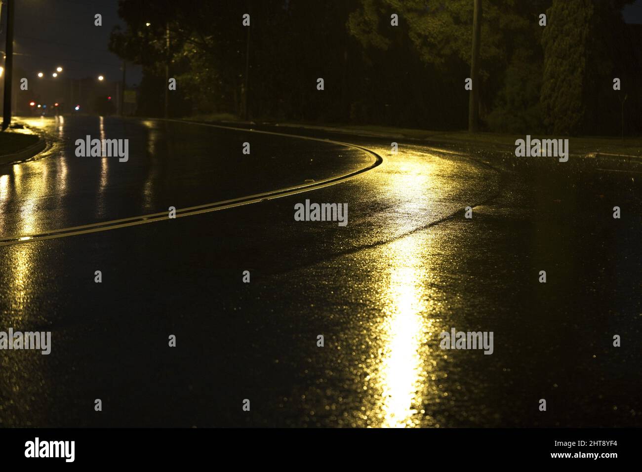 Dark wet road at night illuminated by yellow street lights Stock Photo