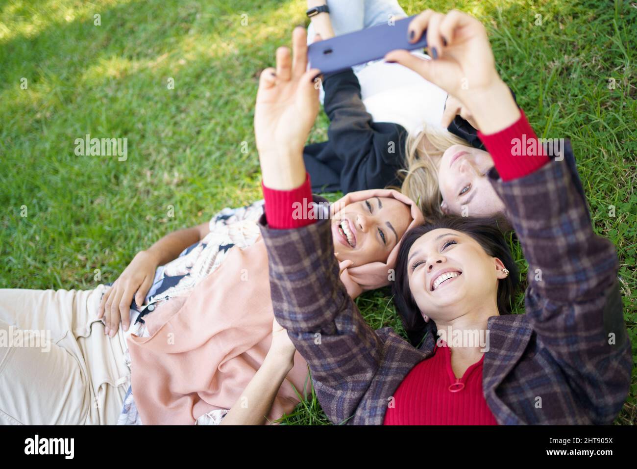 Cheerful diverse women taking selfie on lawn Stock Photo