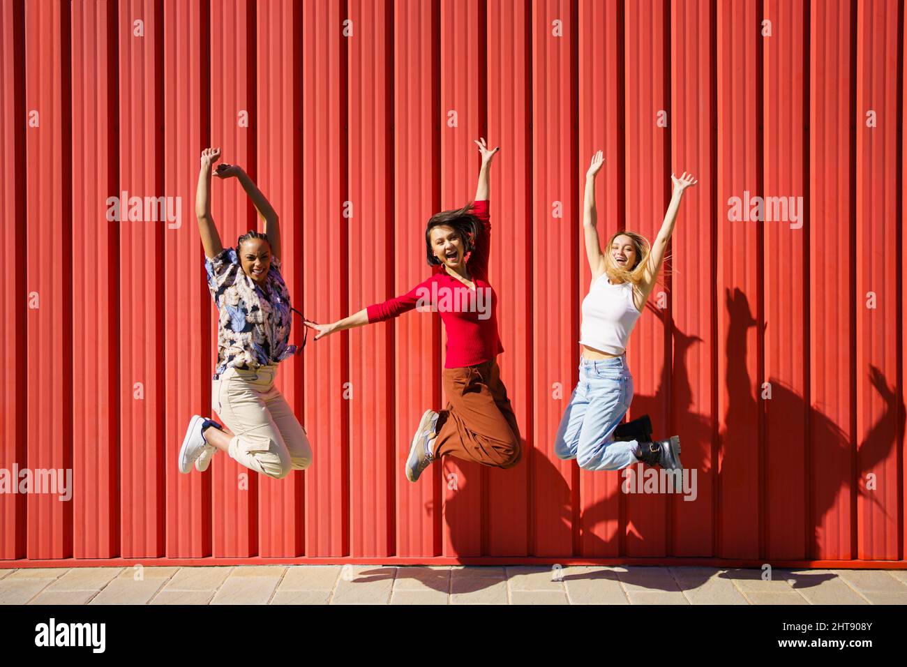 Delighted women jumping near wall Stock Photo