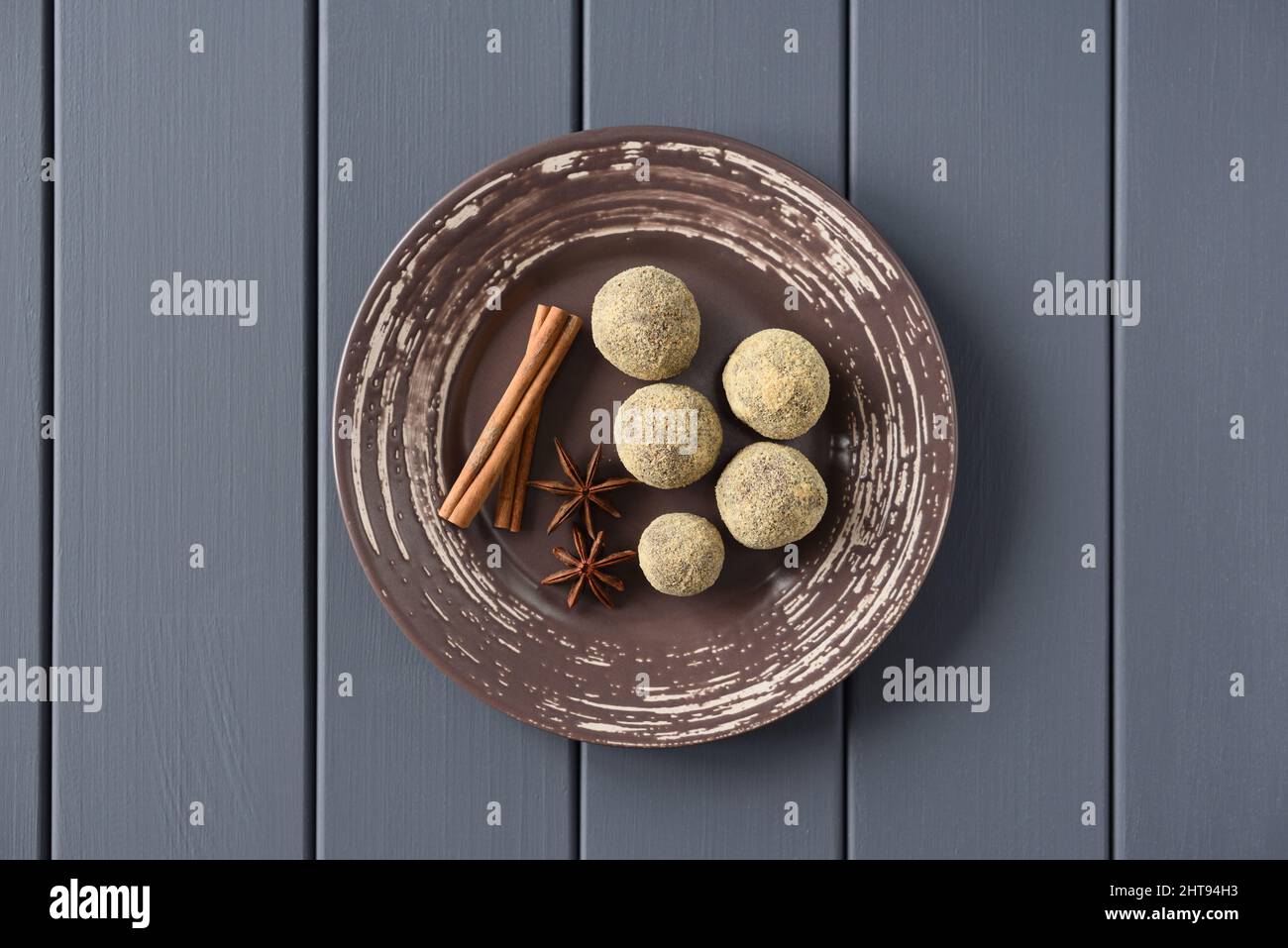 Healthy homemade sweets in bread crumbswith cinnamon stick and star anise on brown plate overhead view Stock Photo