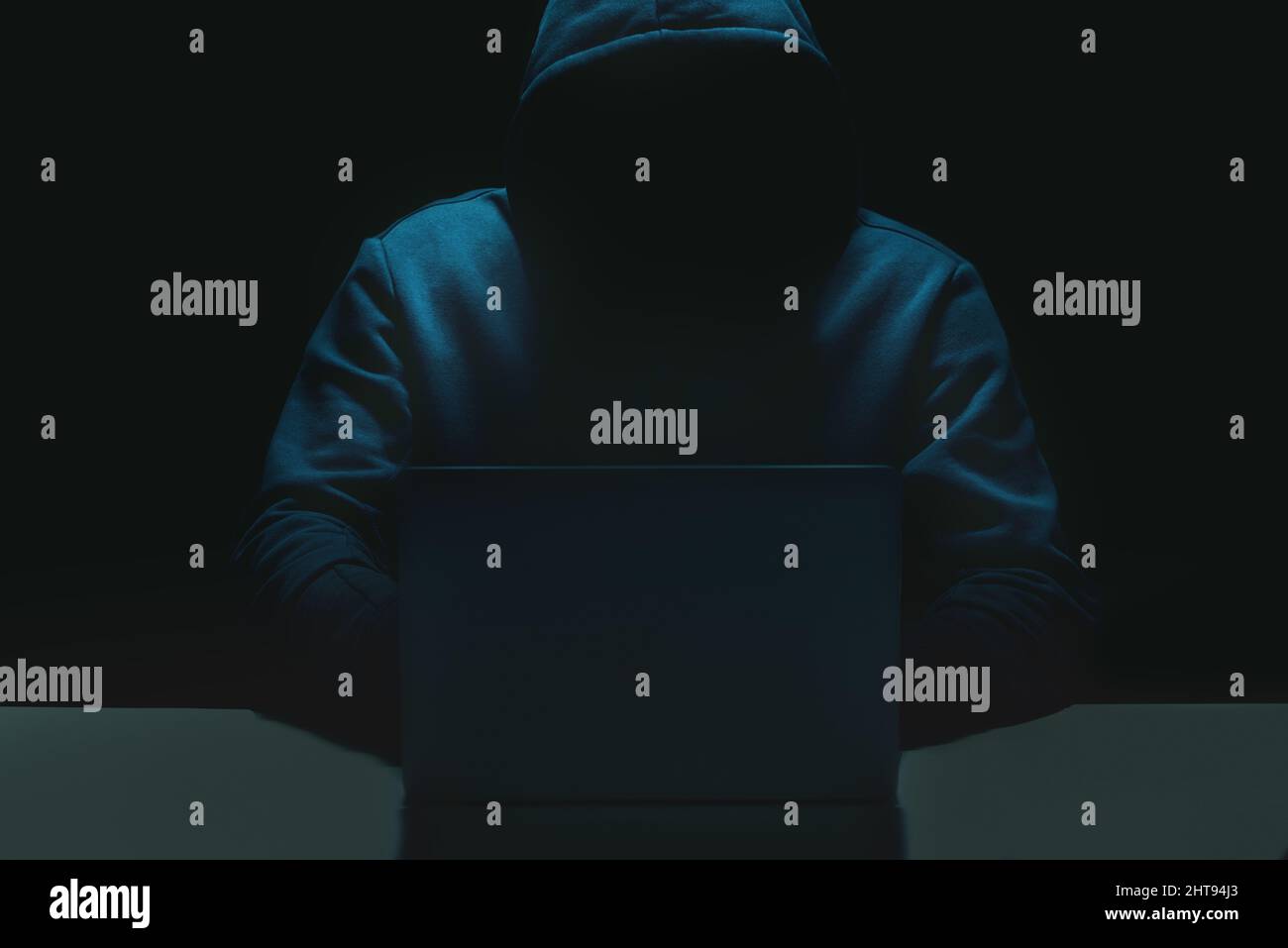 Unrecognizable person using a laptop computer with a hoodie Stock Photo
