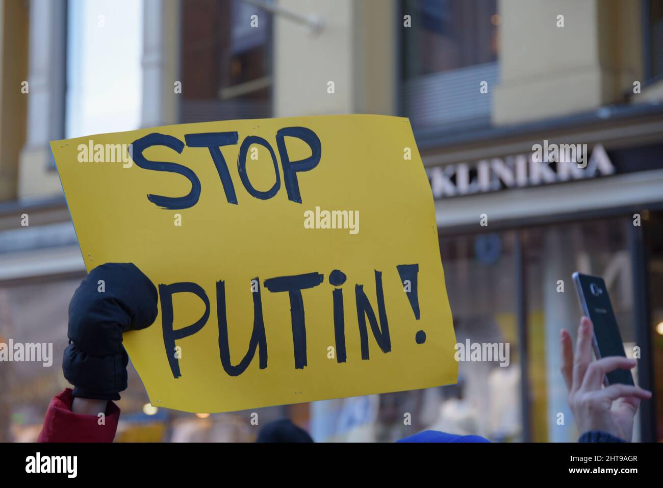 Helsinki, Finland - February 26, 2022: Demonstrator in a rally against Russia’s military actions and occupation in Ukraine carrying sign Stop Putin in Stock Photo