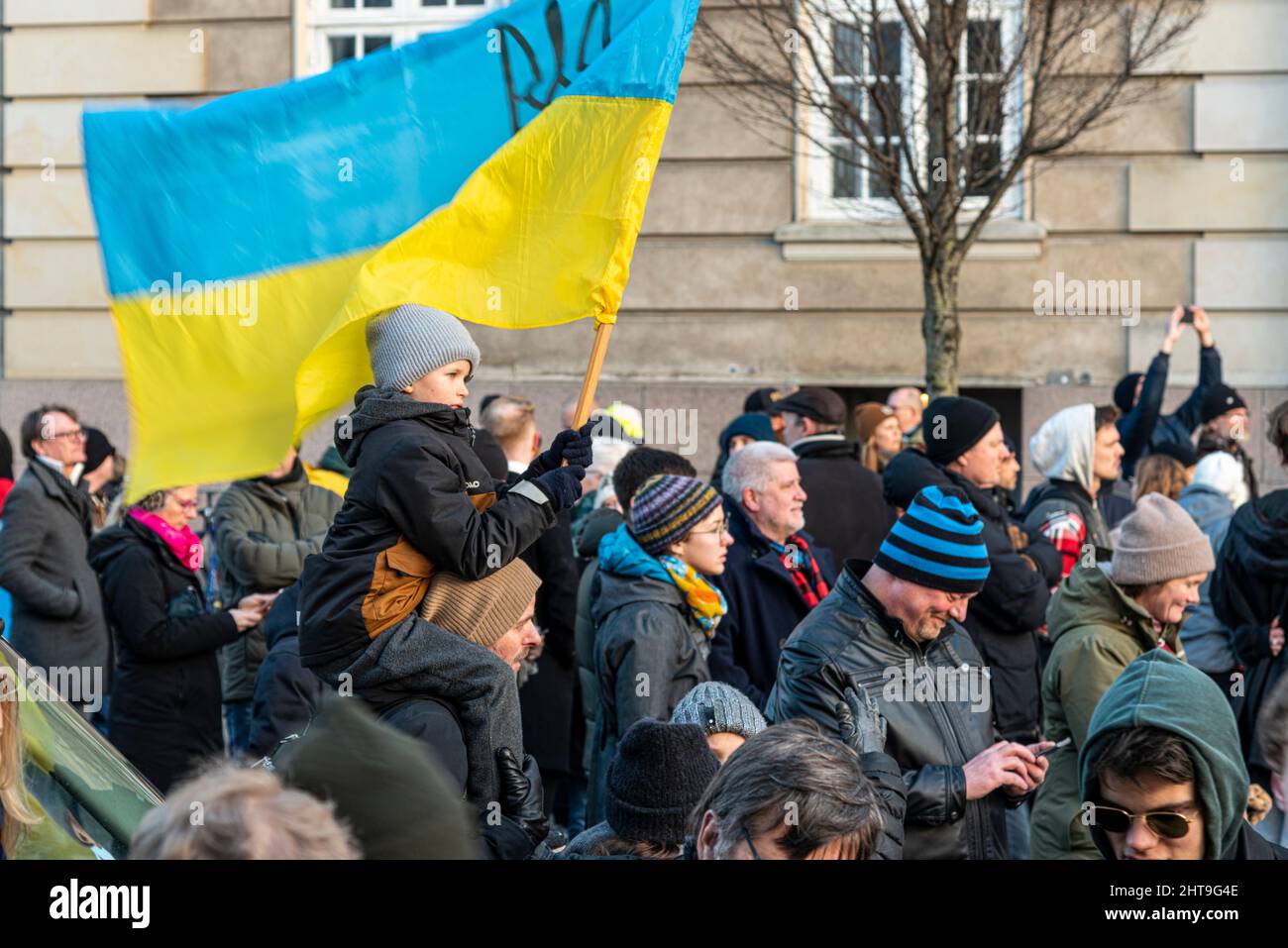 boy riding on his father's shoulders with a Ukrainian flag at the demonstration in front of the Russian embassy in Copenhagen, February 27, 2022 Stock Photo