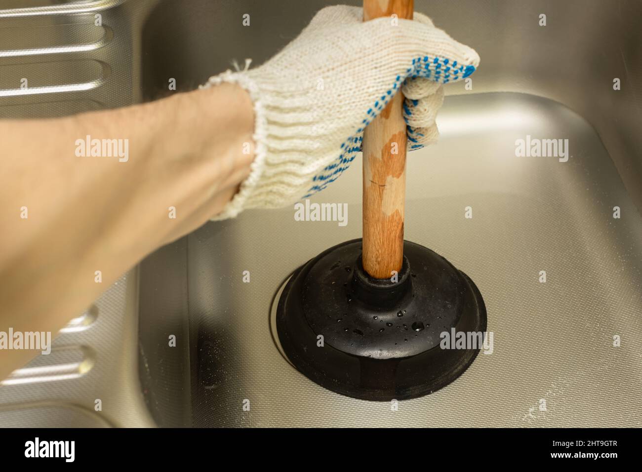 a gloved hand pumps a pipe in the sink with a vantus. High quality photo Stock Photo