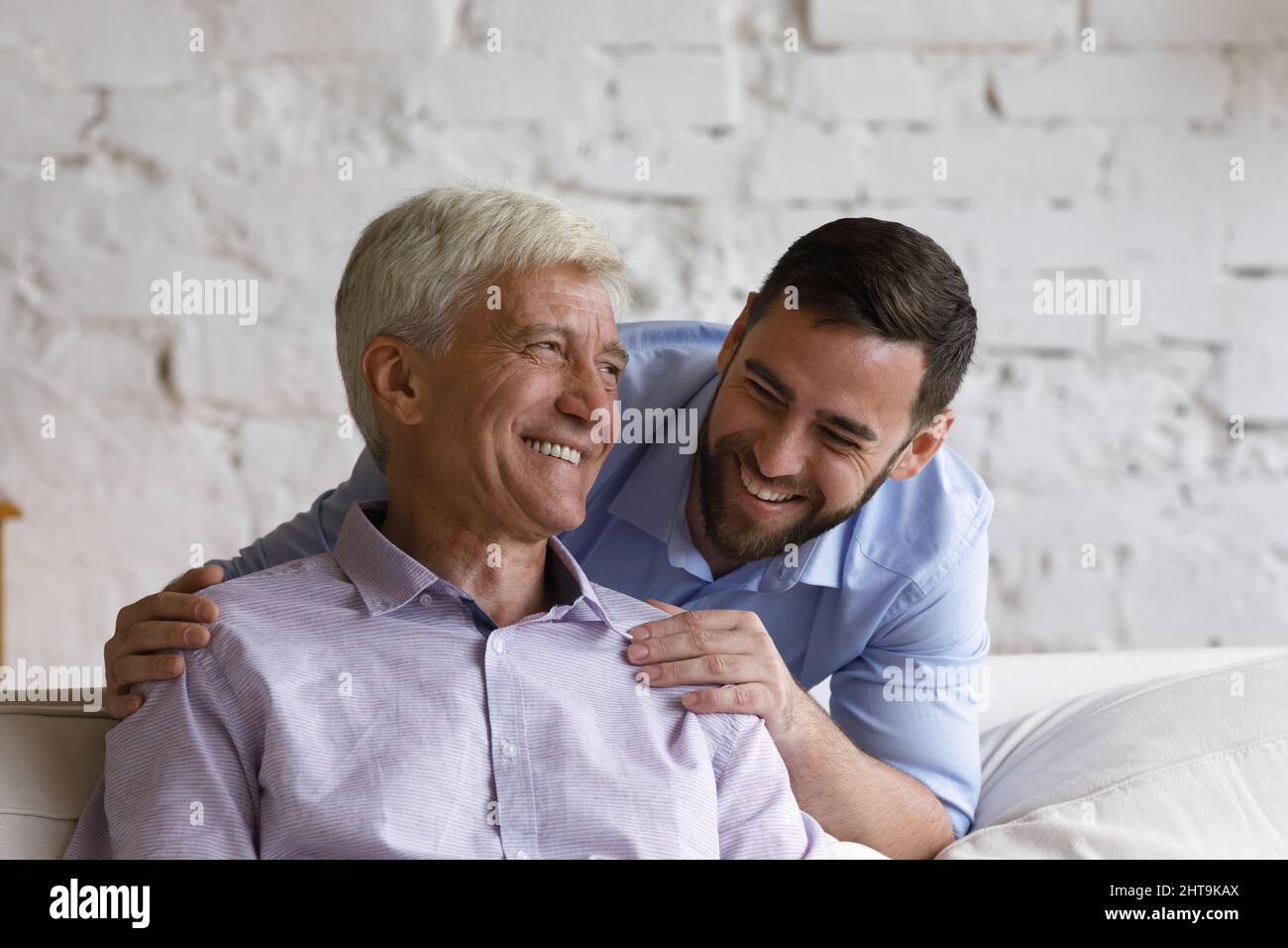 Happy handsome grown up son hugs his elderly father Stock Photo