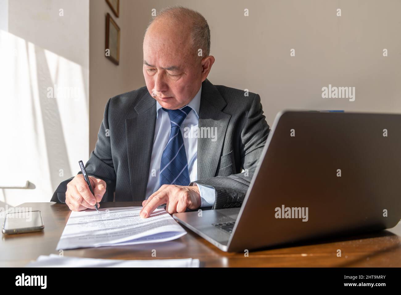A senior executive signing a document in the office. Work, office concept. Stock Photo