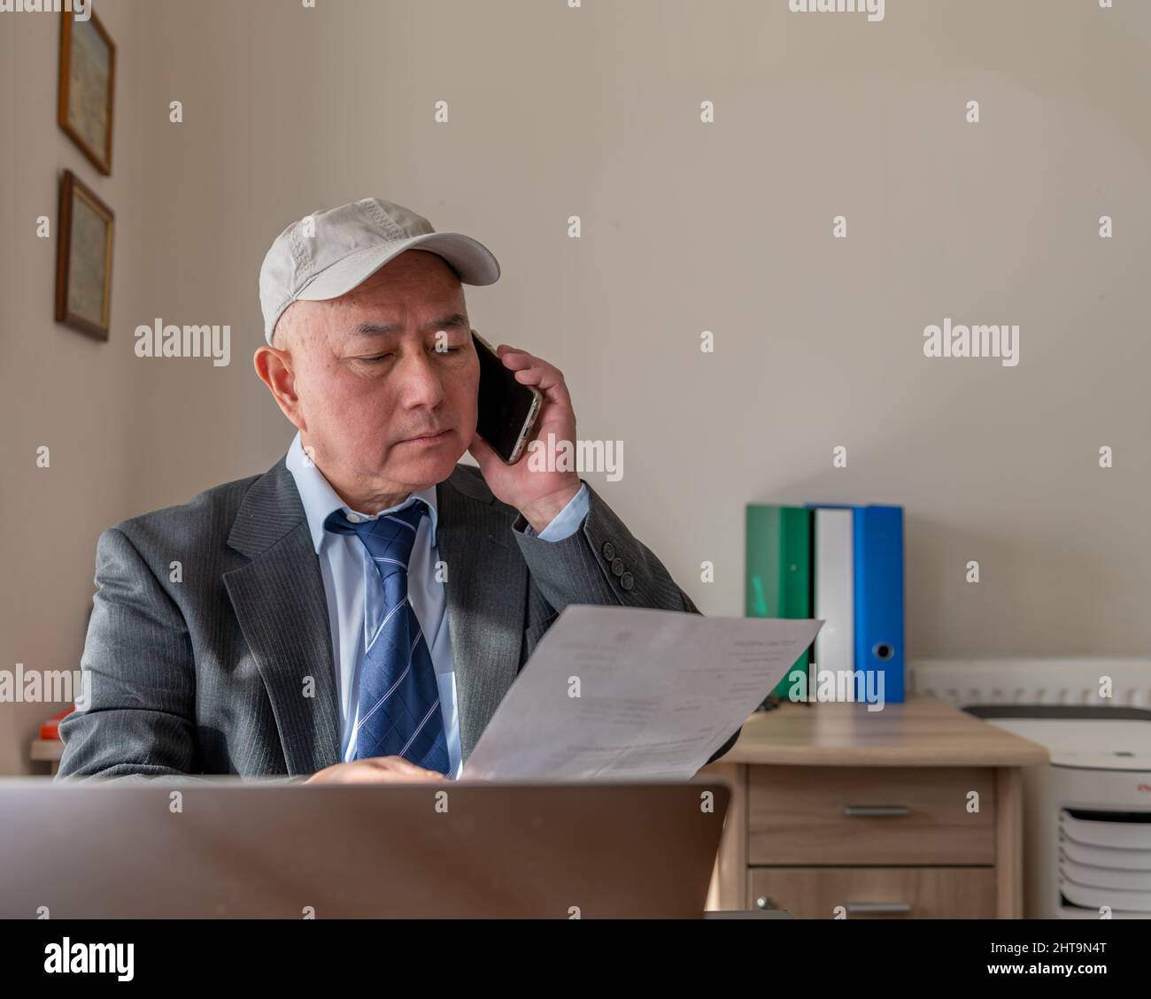 A senior executive in the office on the phone discussing a contract with a client. Stock Photo