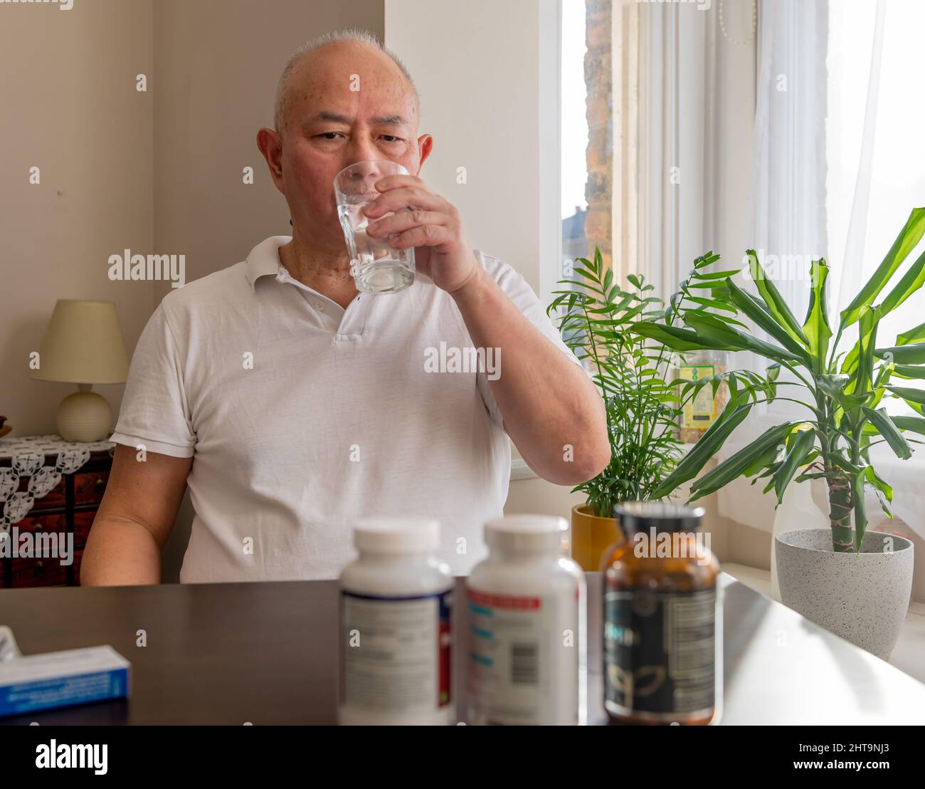 A matured senior man taking medicine and health supplements at home. Stock Photo