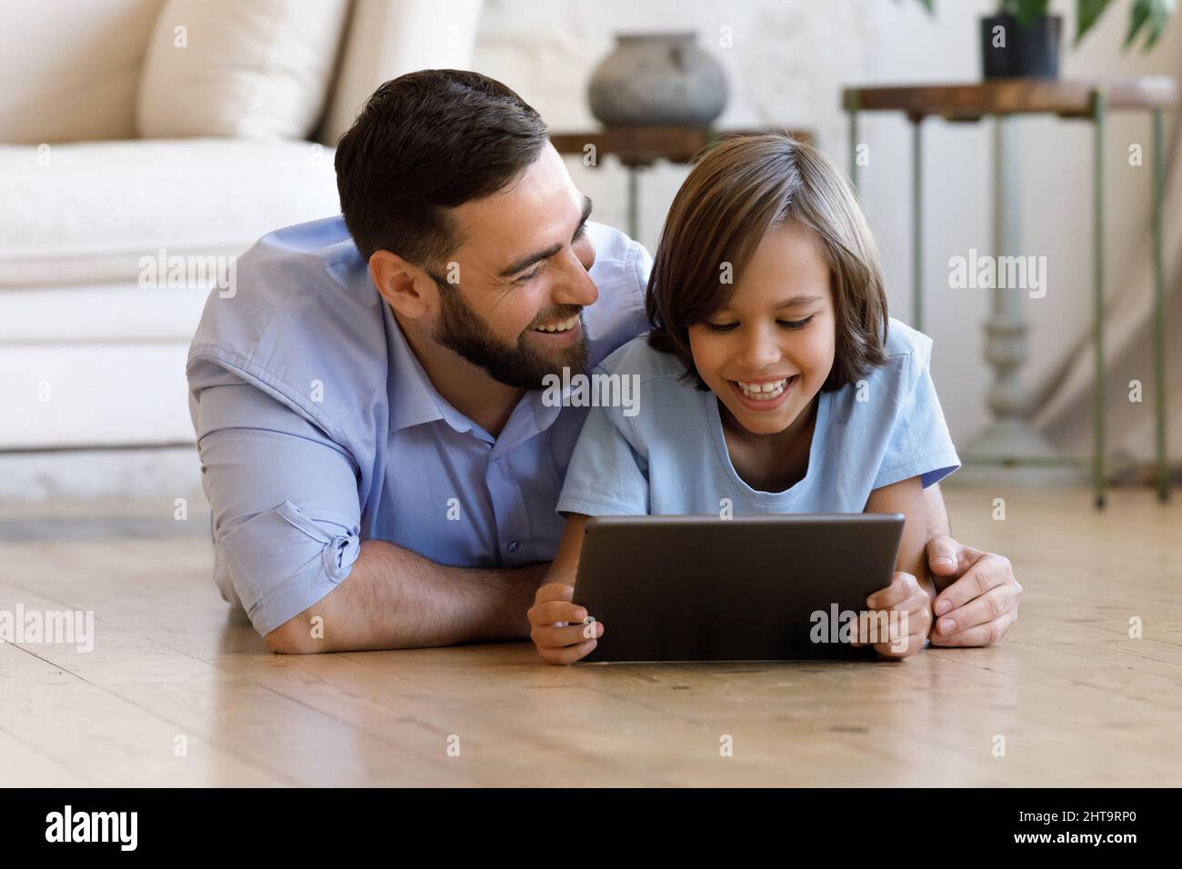 Dad and son lying on floor using digital tablet Stock Photo