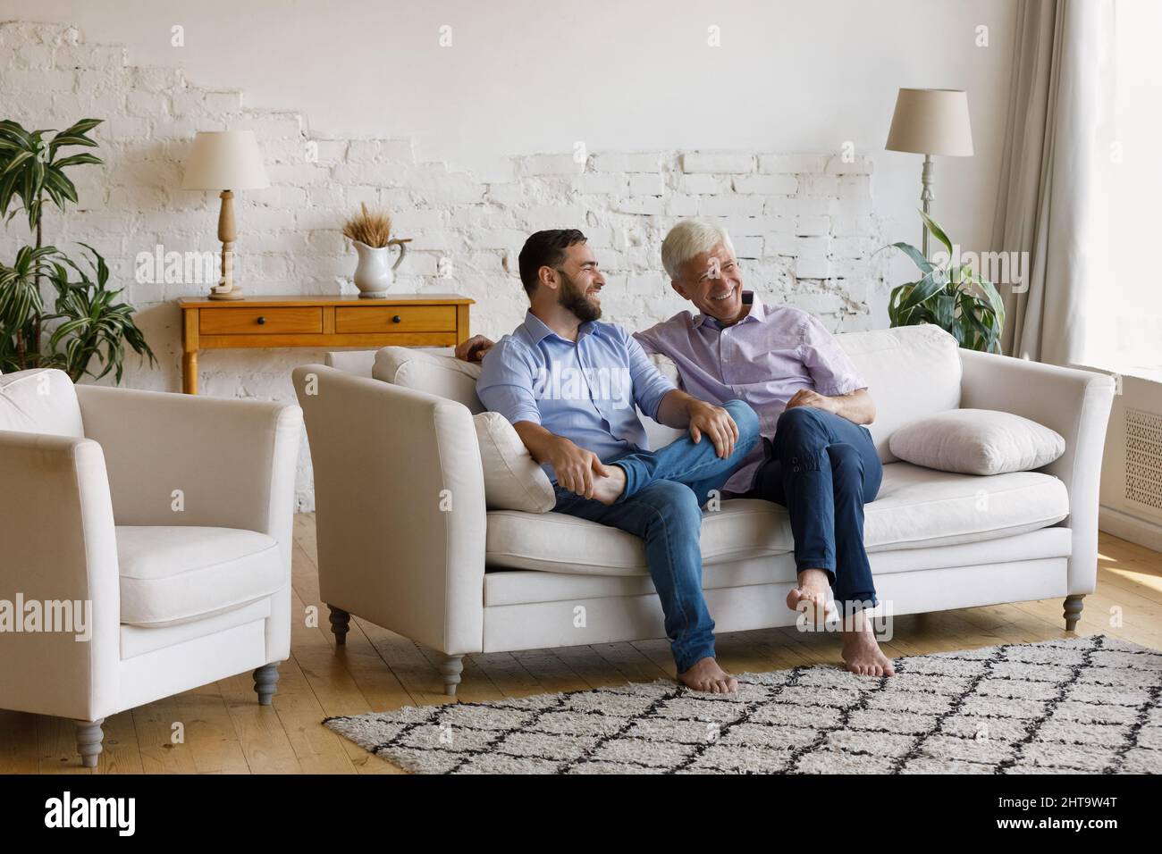 Cheerful man his senior father talking sit on sofa Stock Photo