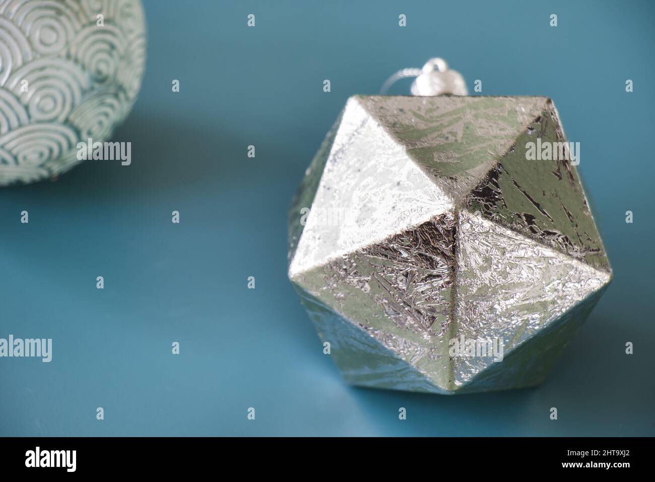 A closeup shot of silver round and icosahedron geometric figures isolated on the blue background Stock Photo