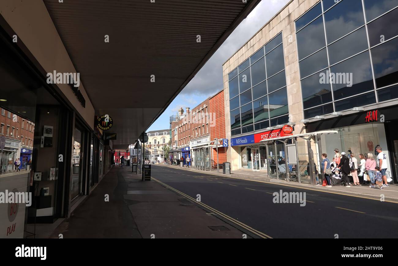 A view of shops, food outlets, and people waiting at the bus stop in