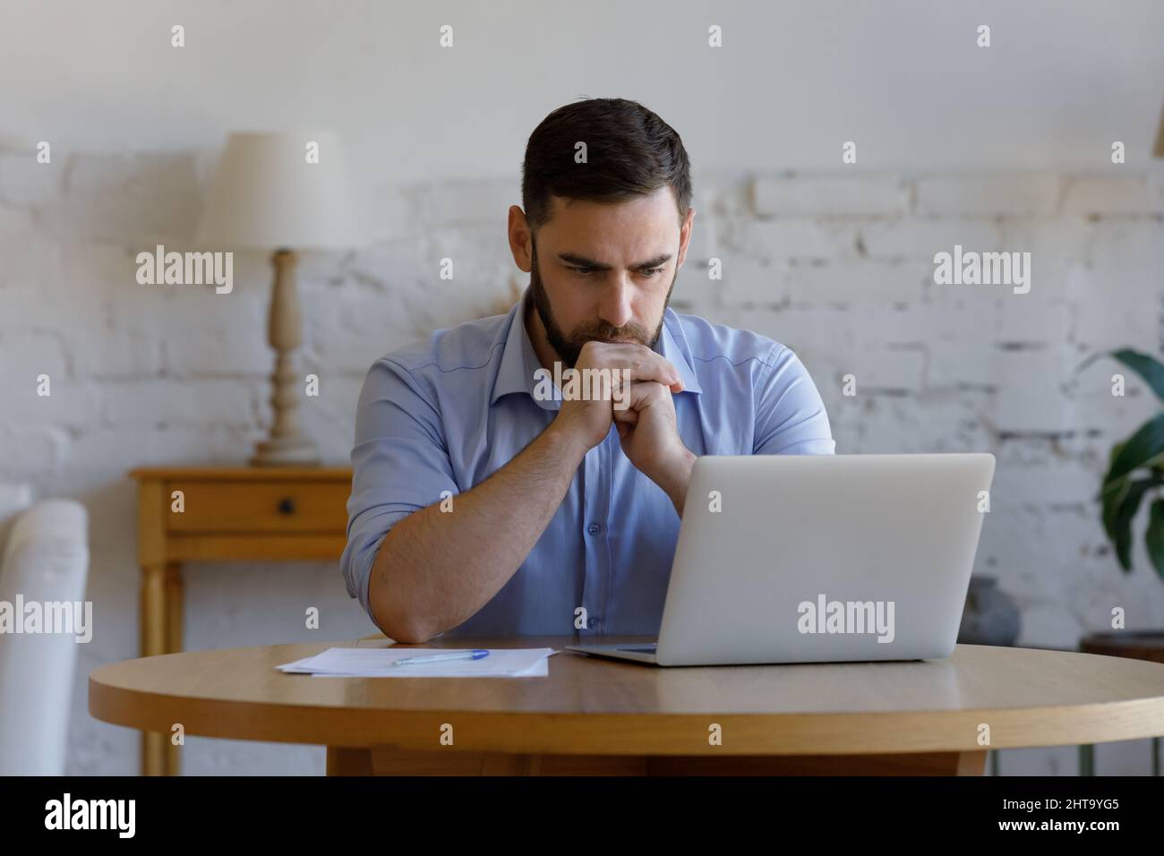 Serious man read e-mail on laptop looks concerned or puzzled Stock Photo