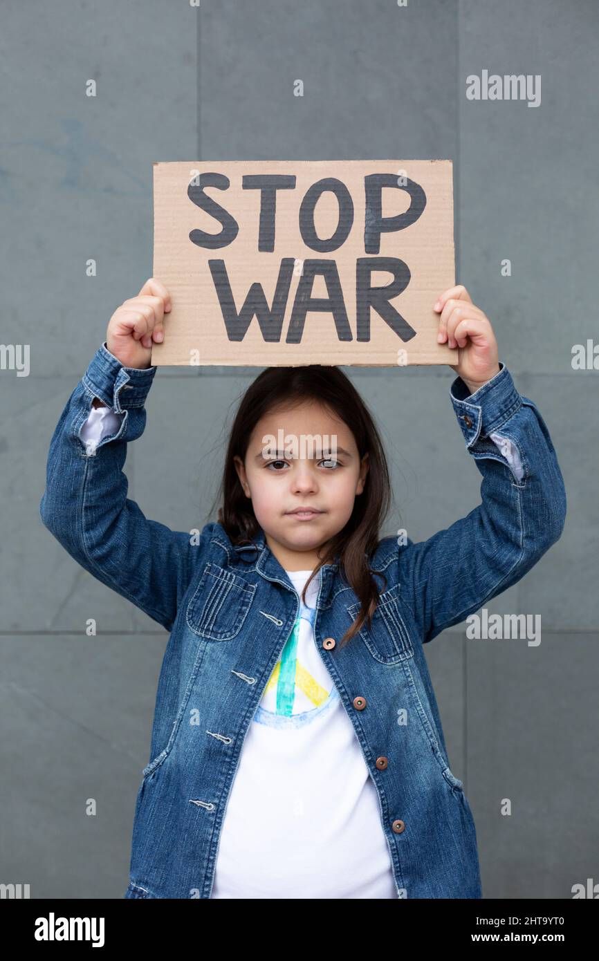 Little girl outdoors holding a handmade sign with the slogan Stop War. Stock Photo