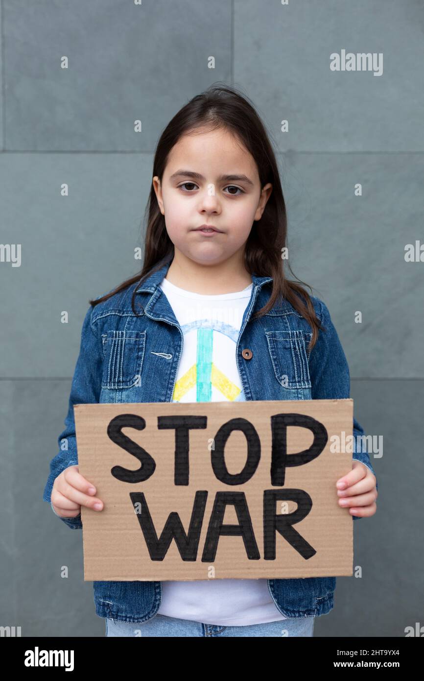 Little child in the street holding a handmade sign with Stop War slogan. Stock Photo
