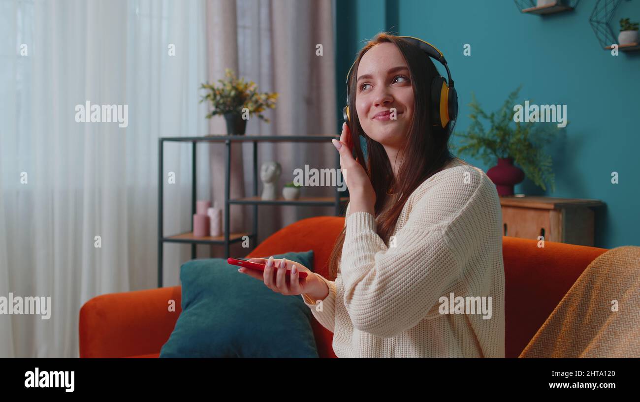 Pretty Caucasian young woman in headphones listening music dancing ...