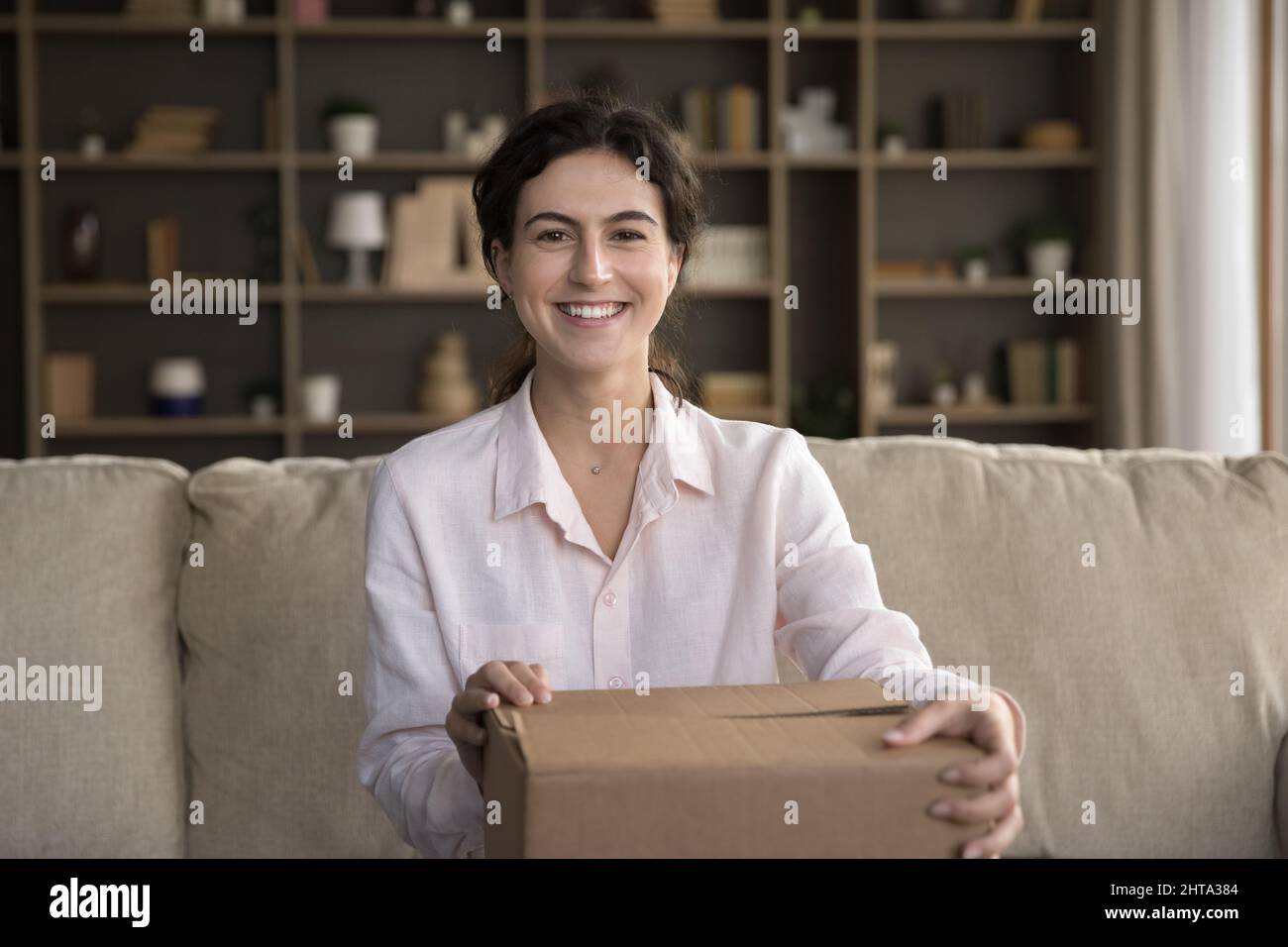 Portrait of smiling young Hispanic woman with carton box. Stock Photo