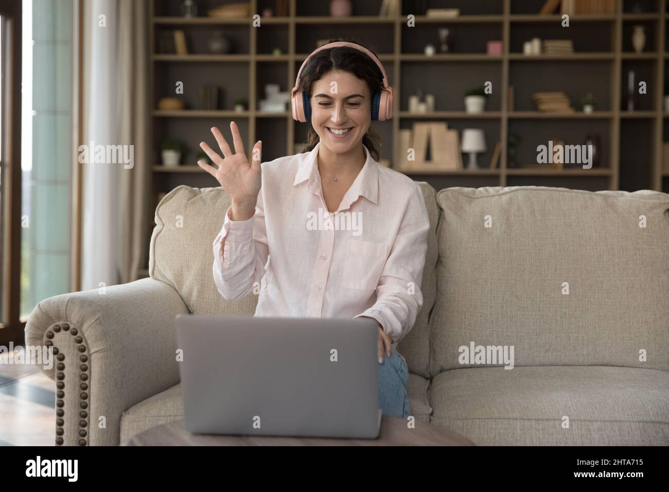 Happy pretty young Hispanic woman in headphones starting video call ...
