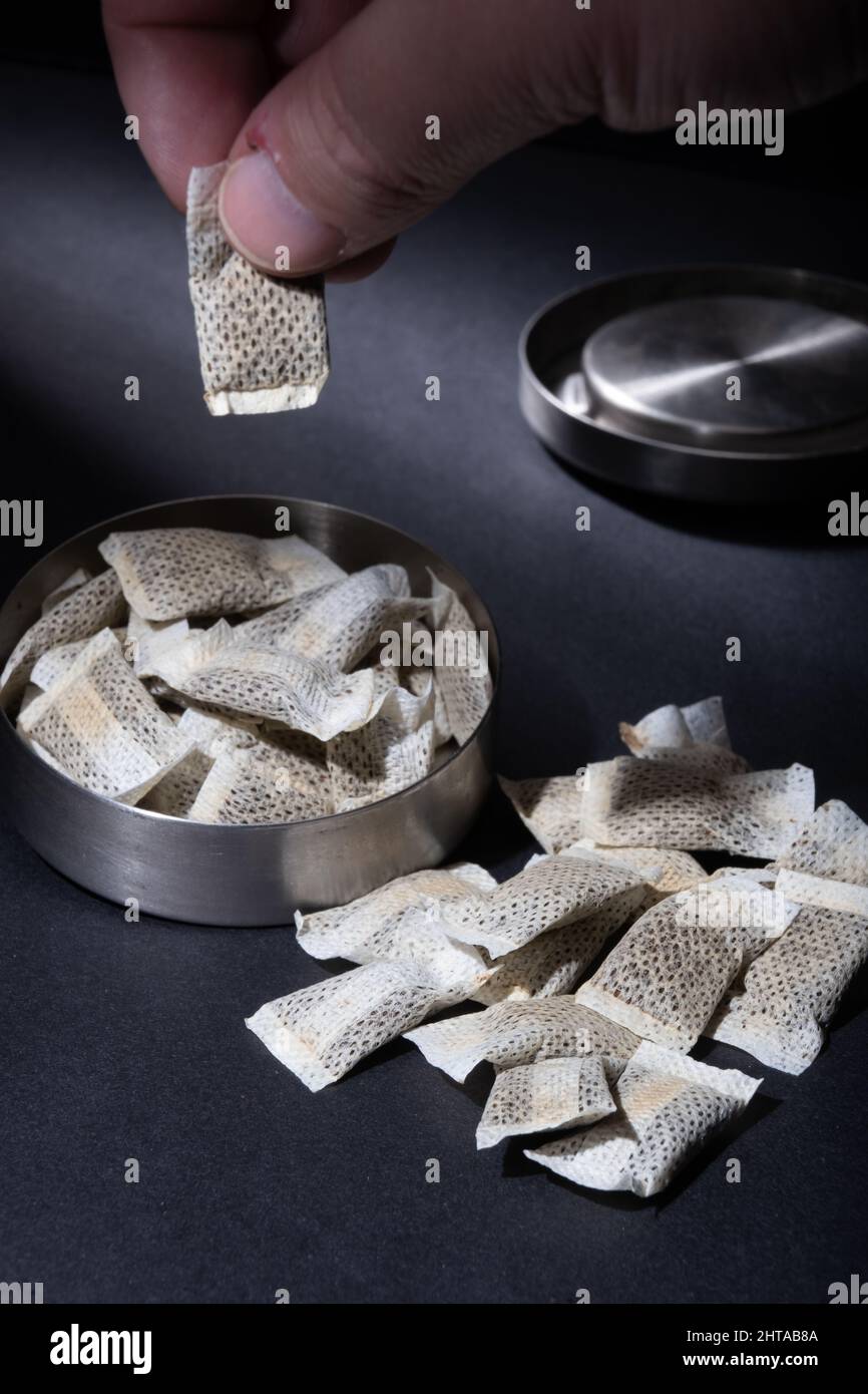 Helsinki / Finland - FEBRUARY 28, 2022: Closeup of metallic Swedish snus  can with white portions of smokeless tobacco pouches against a dark  background Stock Photo