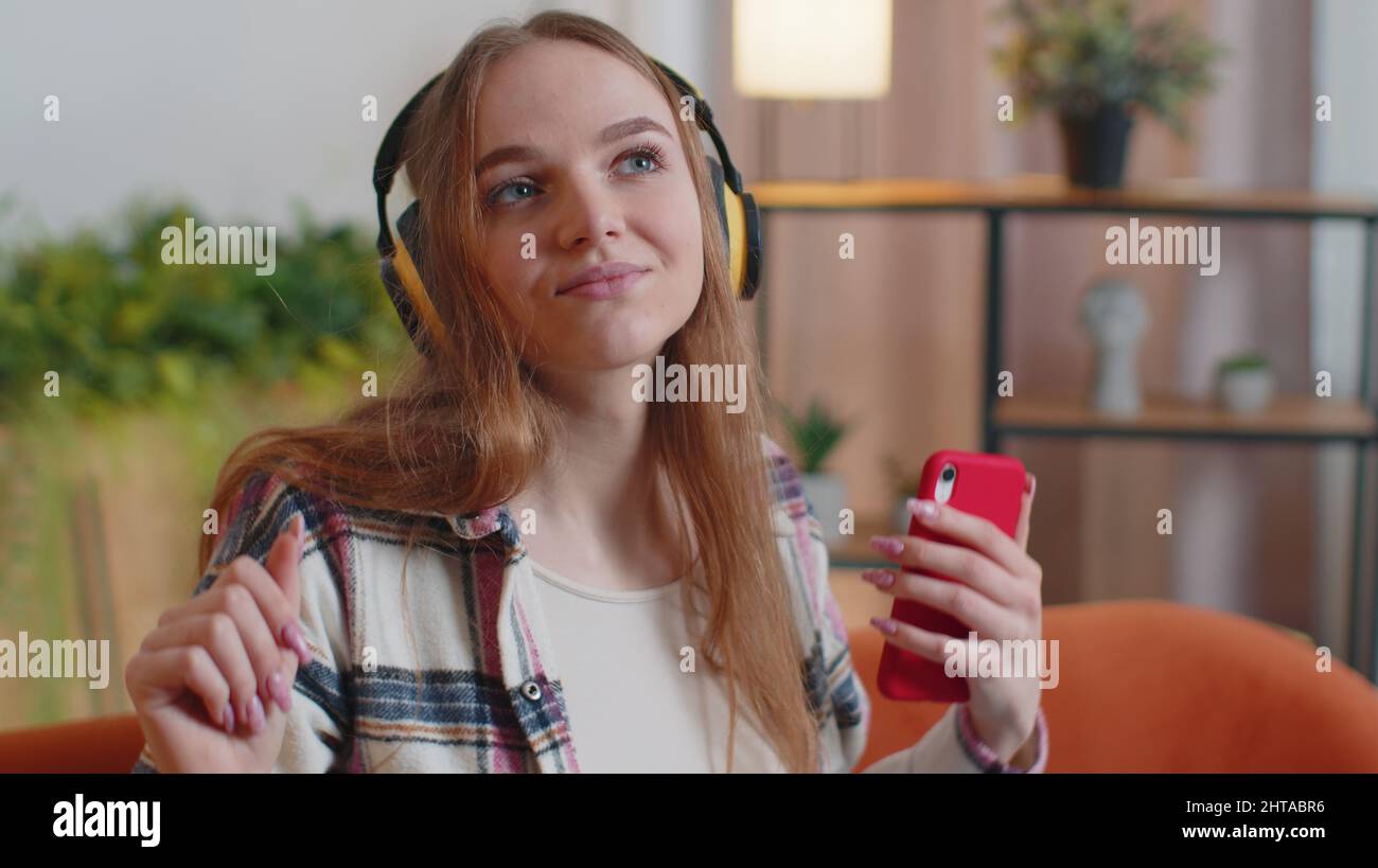 Pretty Caucasian young woman in headphones listening music dancing