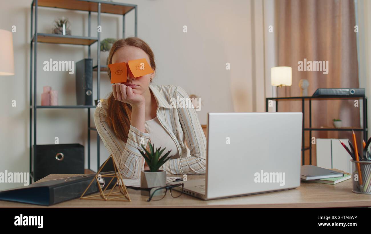 Tired woman teacher using laptop computer with funny stickers on eyes ...