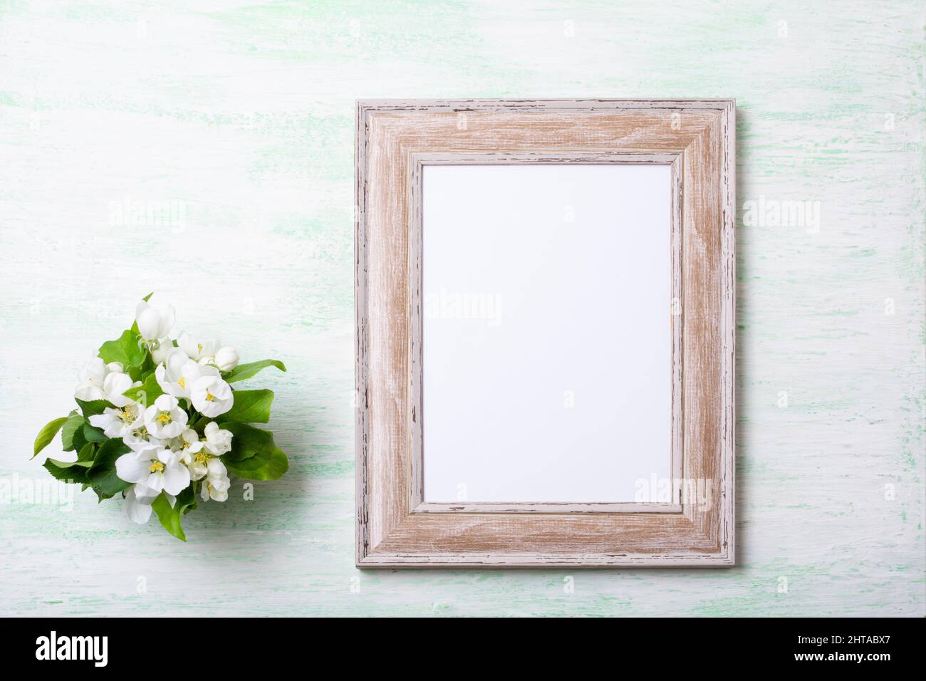 Wooden picture frame mockup with apple blossom on the pale green background. Empty frame mock up for presentation design. Template framing for modern Stock Photo