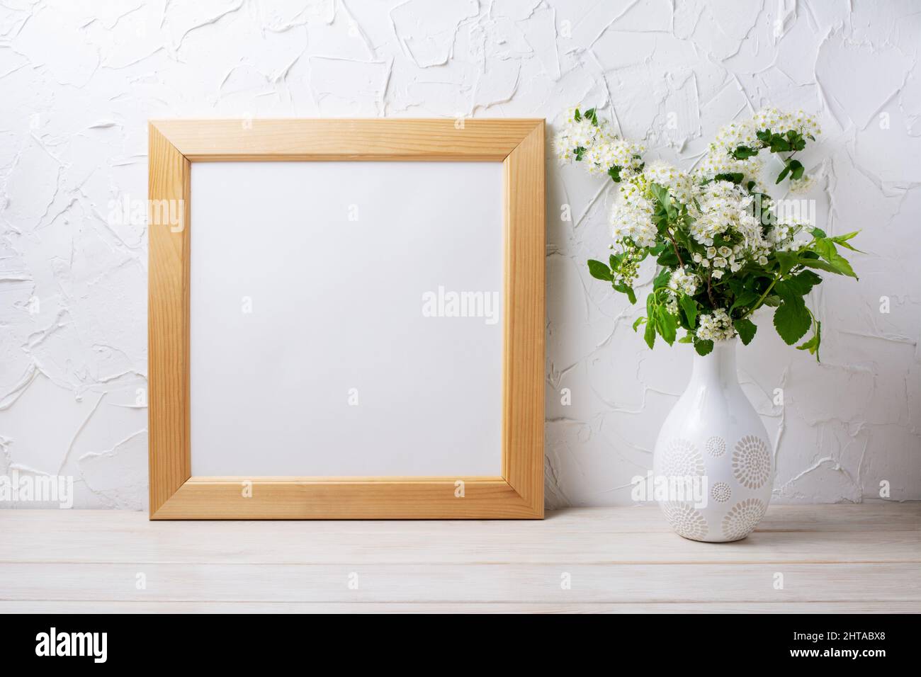 Wooden square picture frame mockup with tender viburnum flowers in the decorated vase. Empty frame mock up for presentation design. Template framing f Stock Photo