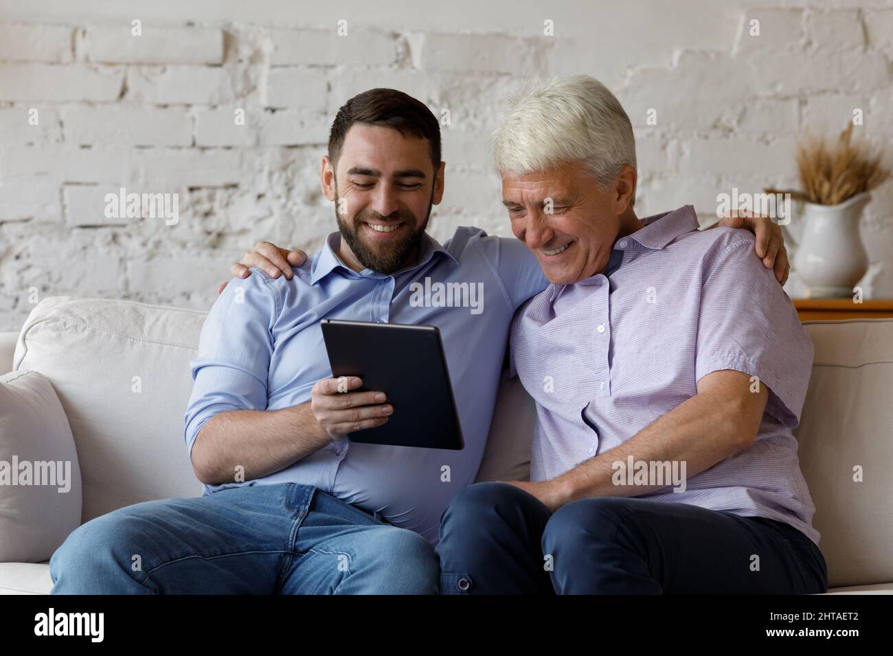 Happy older man his young adult son using digital tablet Stock Photo