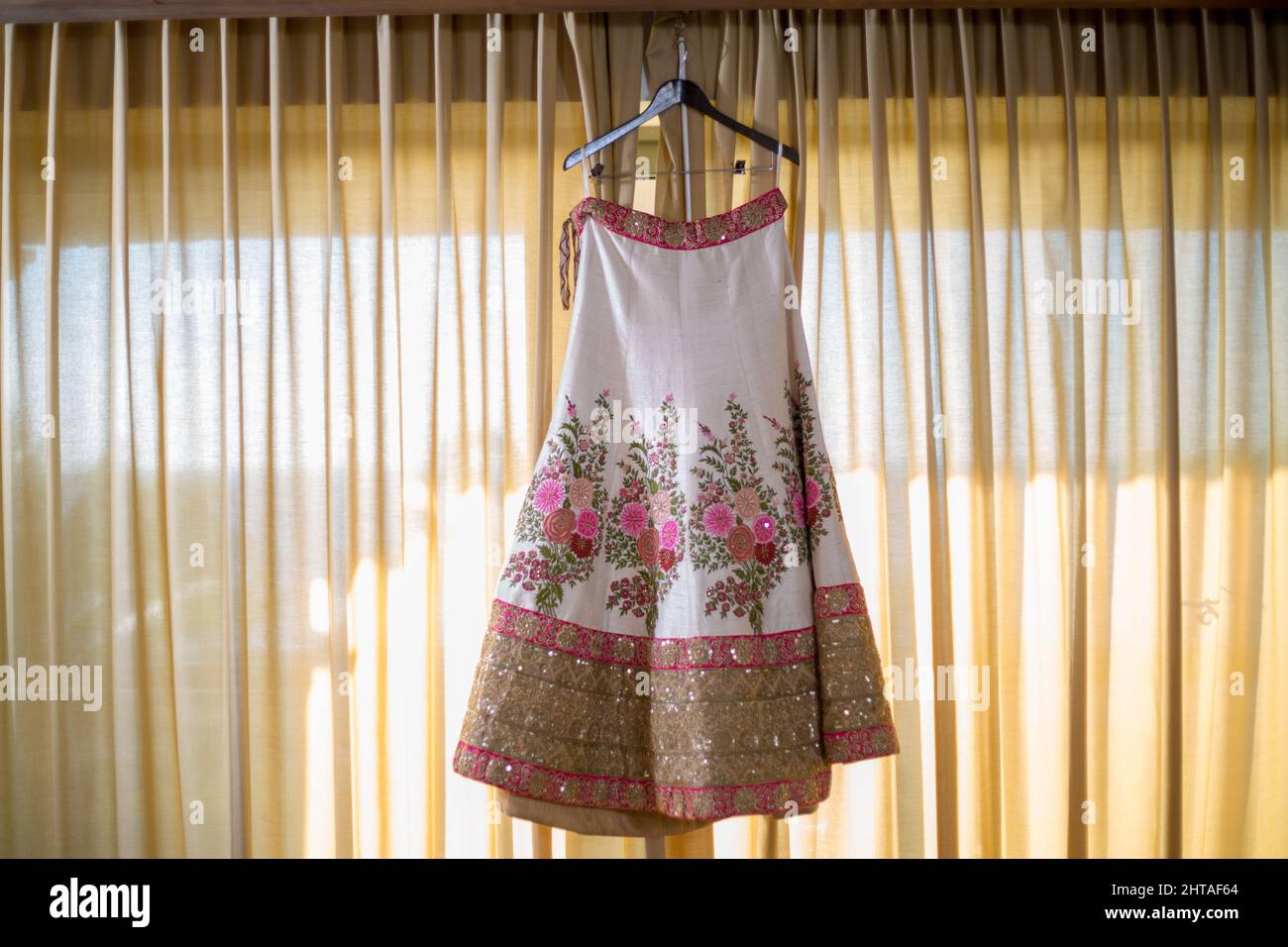 A beautiful traditional Indian wedding dress hanging in front of curtains Stock Photo