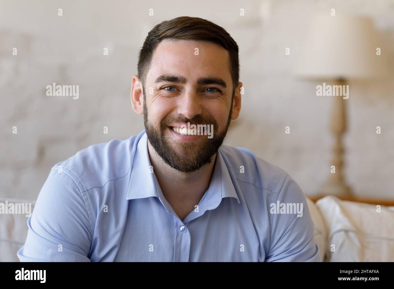 Handsome man sit on sofa at home look at camera Stock Photo