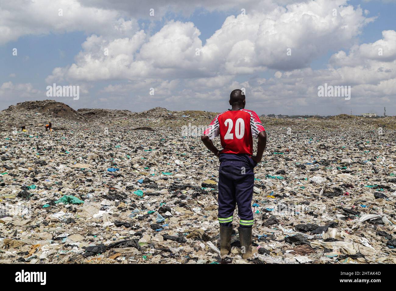 A man in a red tshirt stands on plastic debris at Dandora Dumping site. Discussions to chart a