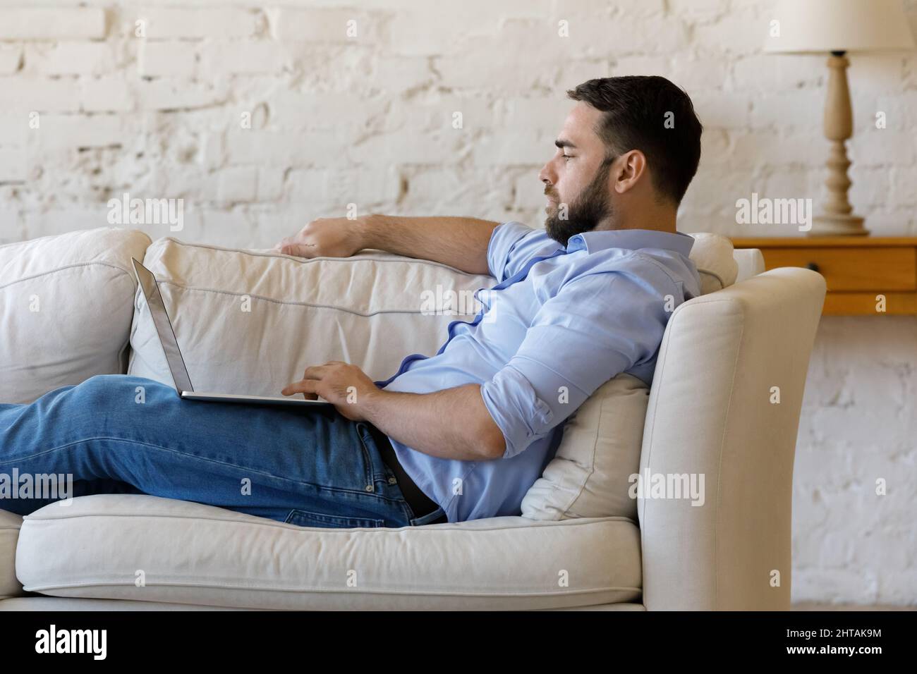 Side view serious man sit on couch with laptop Stock Photo