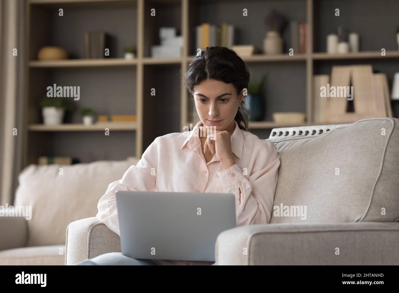 Focused millennial Hispanic woman working on freelance project on computer. Stock Photo