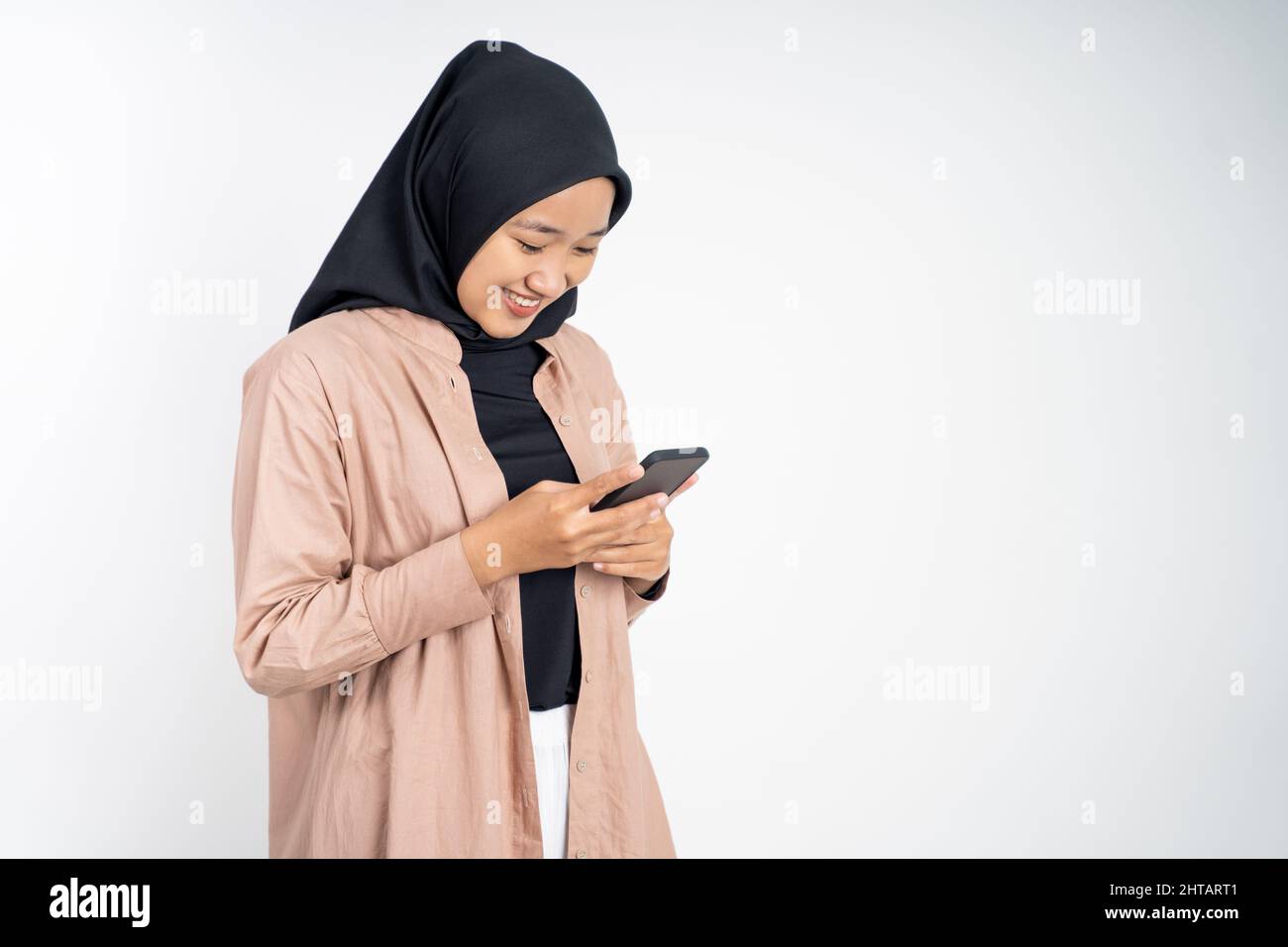 asian woman in hijab smiling while using a cell phone Stock Photo - Alamy