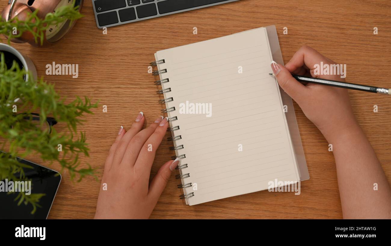 Empty Hand Writing Top shot, Female hand writing on empty spiral notepad on wooden ...