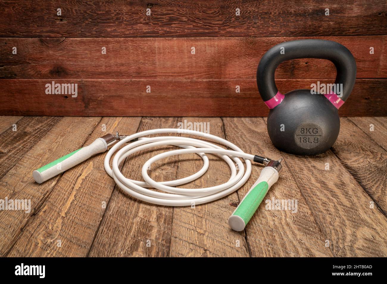 heavy fitness jump rope and iron kettlebell on rustic, weathered wood ...