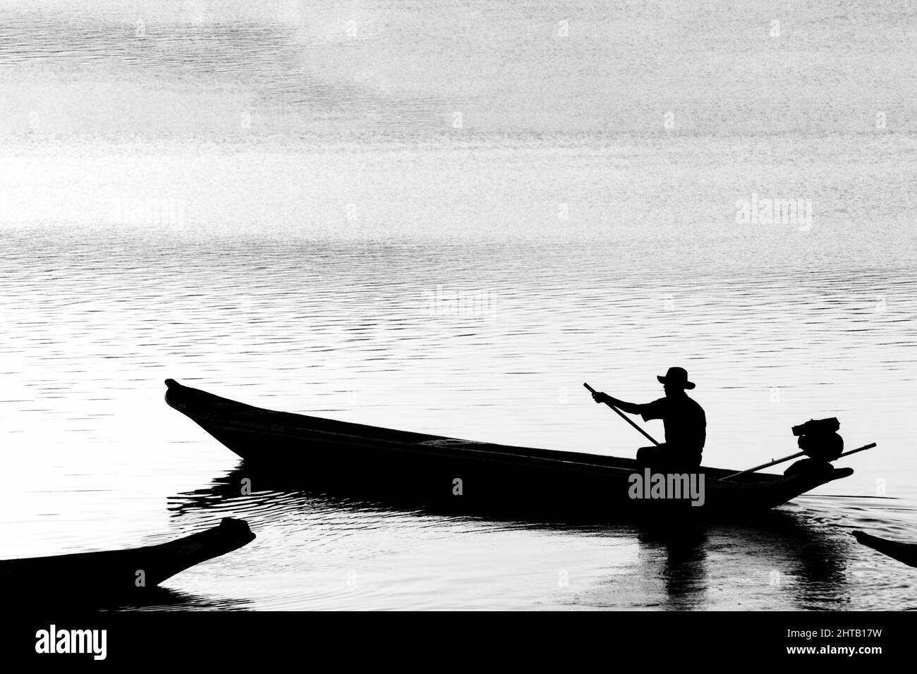 Closeup of a silhouette at sunset of a fisherman in his boat on the grandiose Paraguacu river Stock Photo
