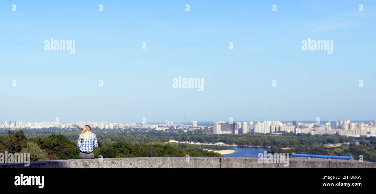 An Ukrainian woman enjoying the views of Eastern and North Eastern Kyiv from the park of eternal glory in kyiv, Ukraine. Stock Photo