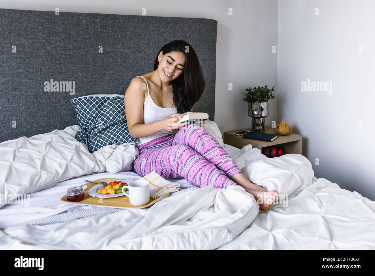 Young latin woman enjoying breakfast in bed at home in Mexico Latin America Stock Photo